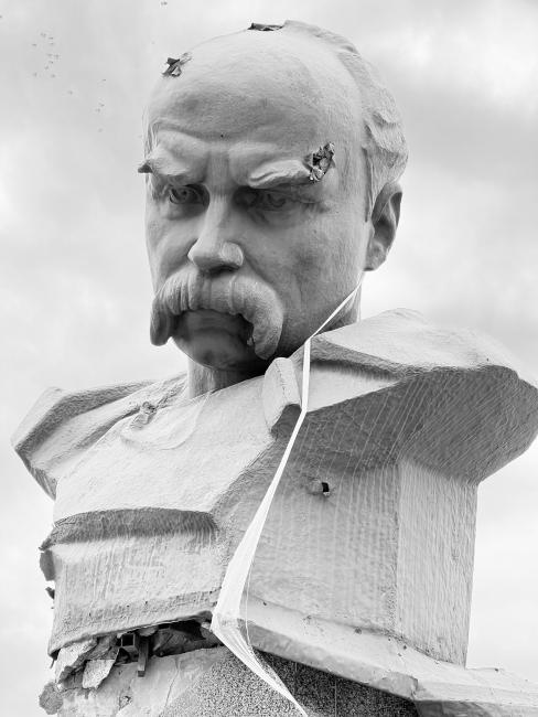 Steel bust of a man with a moustache and bullets holes through the head